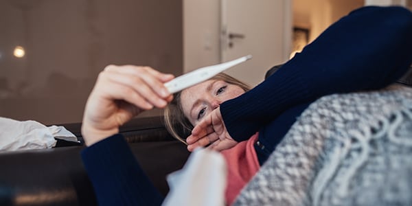 Person checking their temperature with a digital thermometer