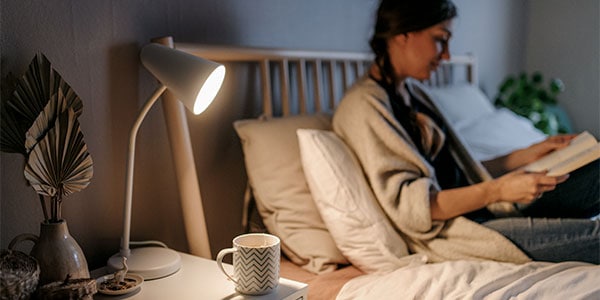 Woman reading on her bed: 40% of Australians aren't getting enough sleep.