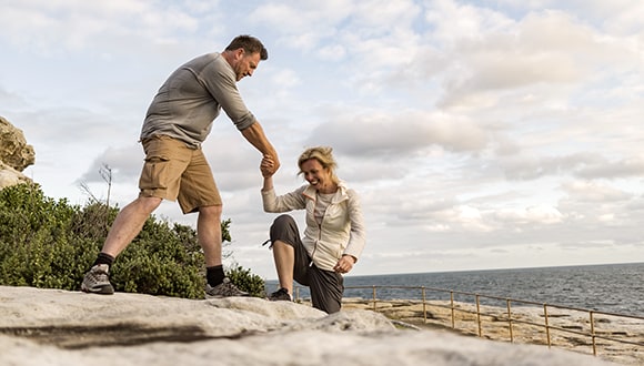 Photo of a male helping his partner(female) up a rock