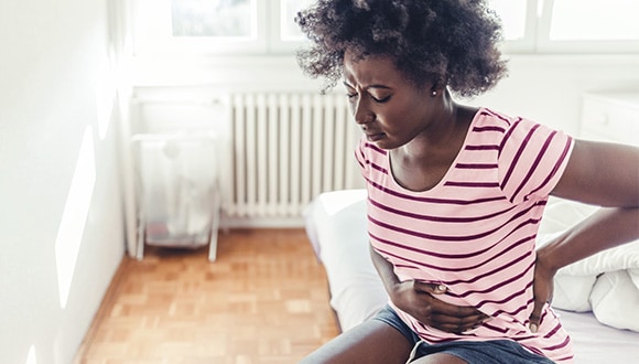 Woman with signs of endometriosis holding her stomach in pain