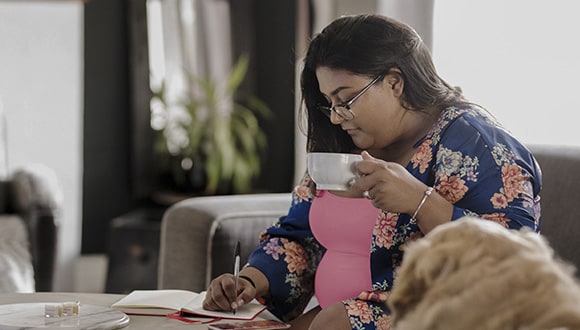 Woman writing down her endometriosis signs and symptoms into monthly tracker