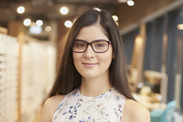 Girl wearing glasses sitting in eating an apple