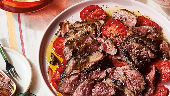 Grilled lamb shoulder recipe served with garlicky tomatoes