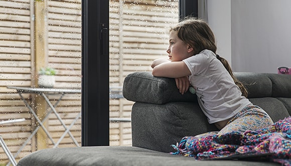 child on sofa looking out a window