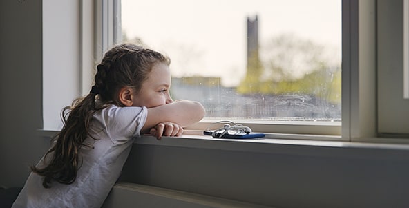 A girl looking out of a window while thinking