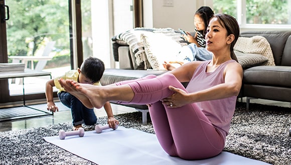 Woman doing yoga on a mat in the lounge room