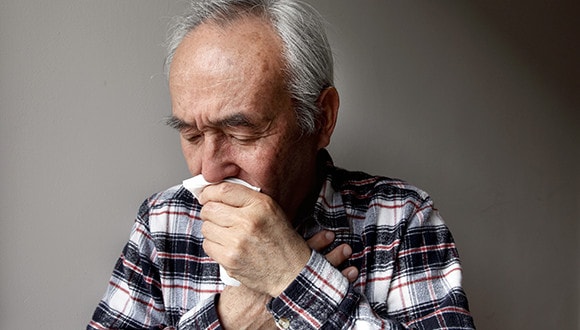 A man coughing into a handkerchief