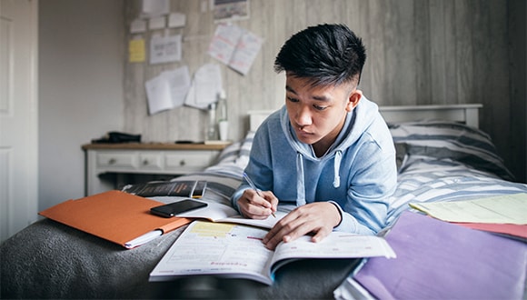 A student studying on their bed